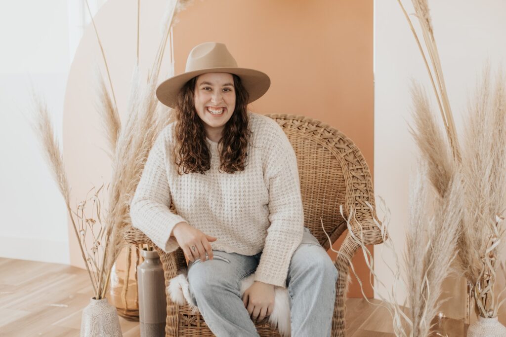 woman in white knit sweater and blue denim jeans sitting on brown wicker chair