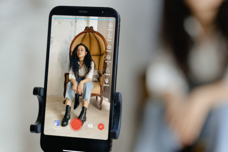 A close up shot of a smartphone recording a woman sitting on a chair