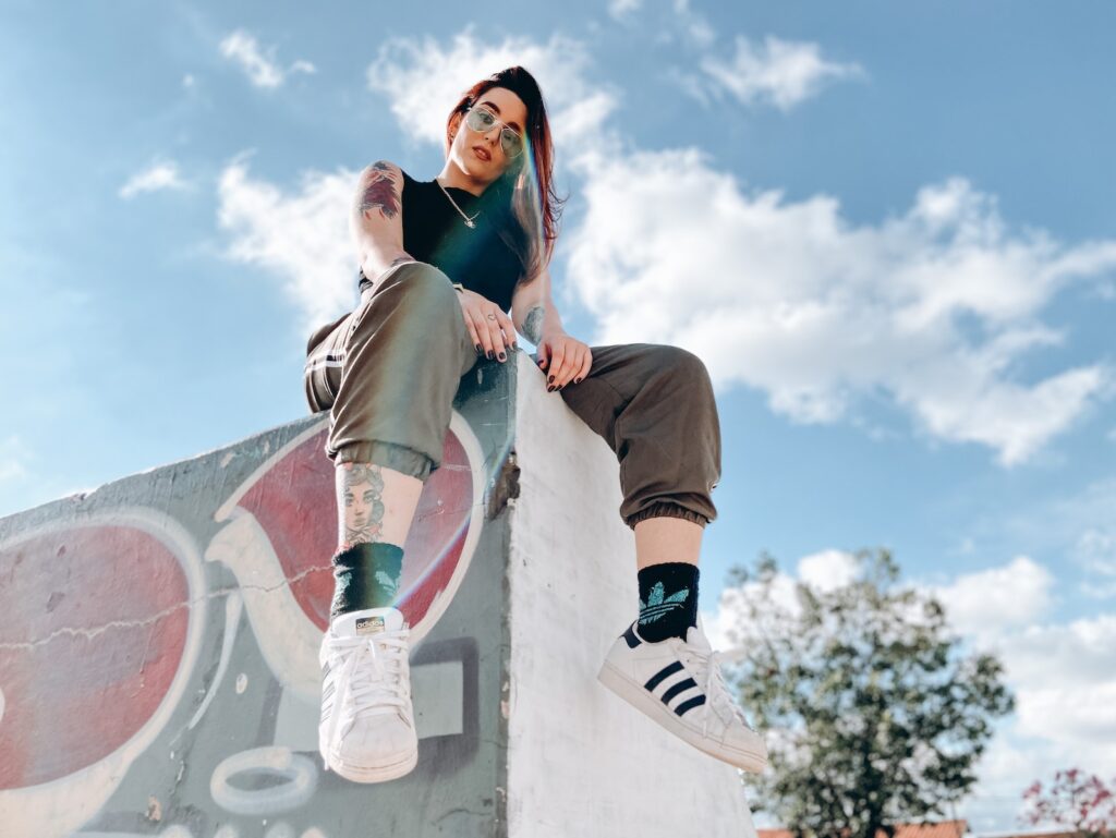 Rebellious tattooed lady relaxing in skate park on sunny day