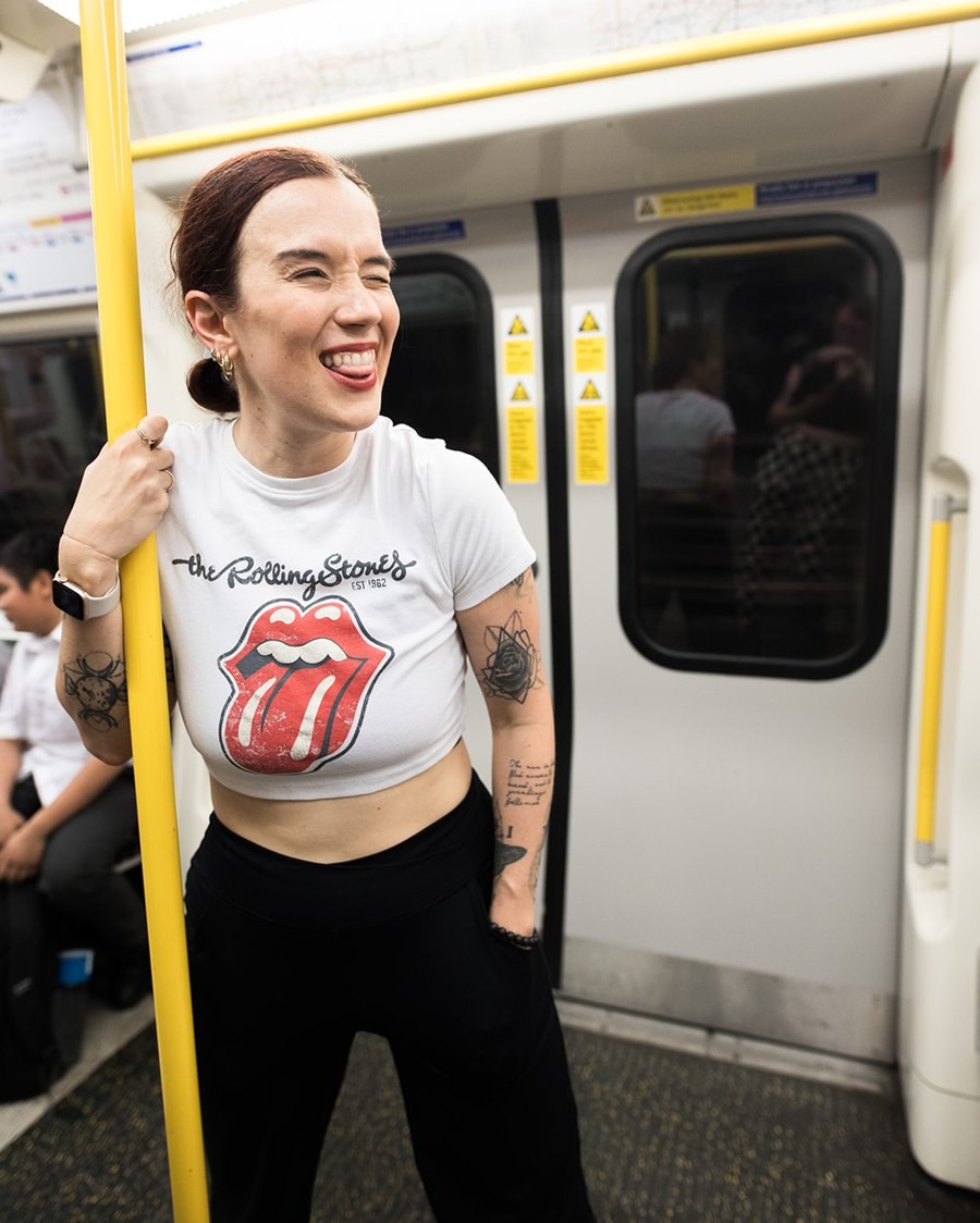 Fab Giovanetti laughing on a London Underground train, holding a yellow pole