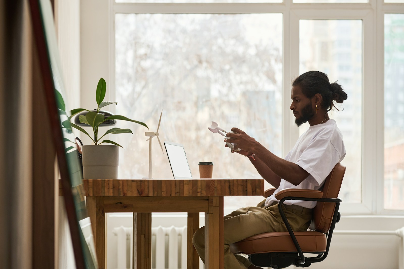 A man works at his desk near a window.